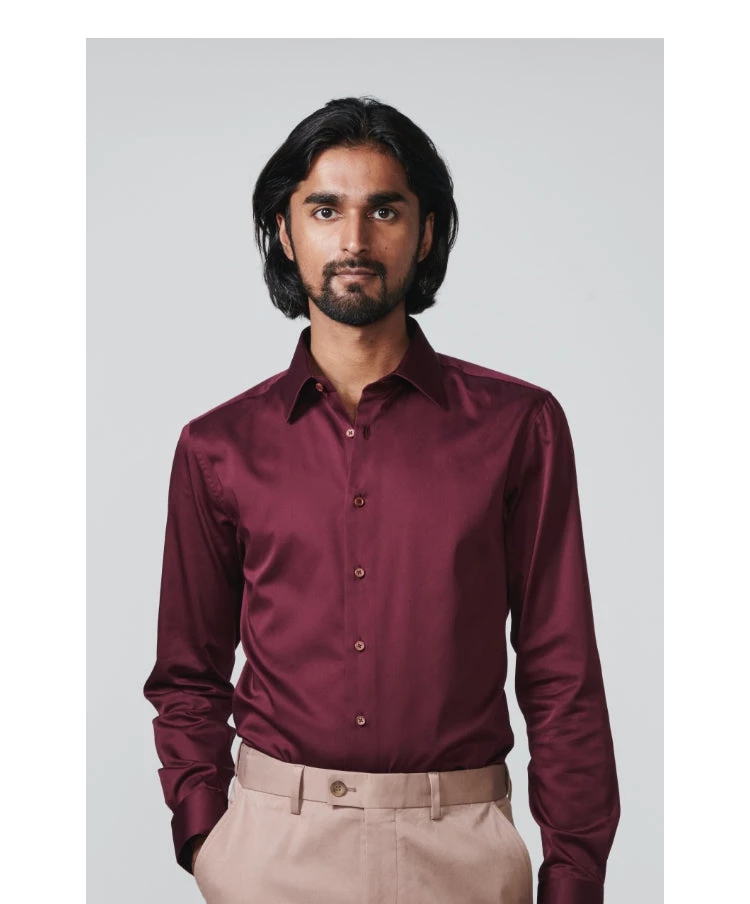 Man looking straight ahead wearing a long sleeve burgurndy shirt
